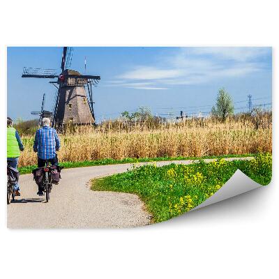 Fototapeta Cyklisté na cestě s výhledem na větrný mlýn