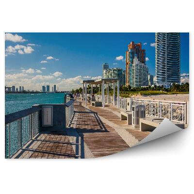 Samolepící fototapeta Molo pláž oceán mrakodrapy palmy lidé tmavé mraky